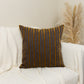 a white couch with a brown and blue striped pillow