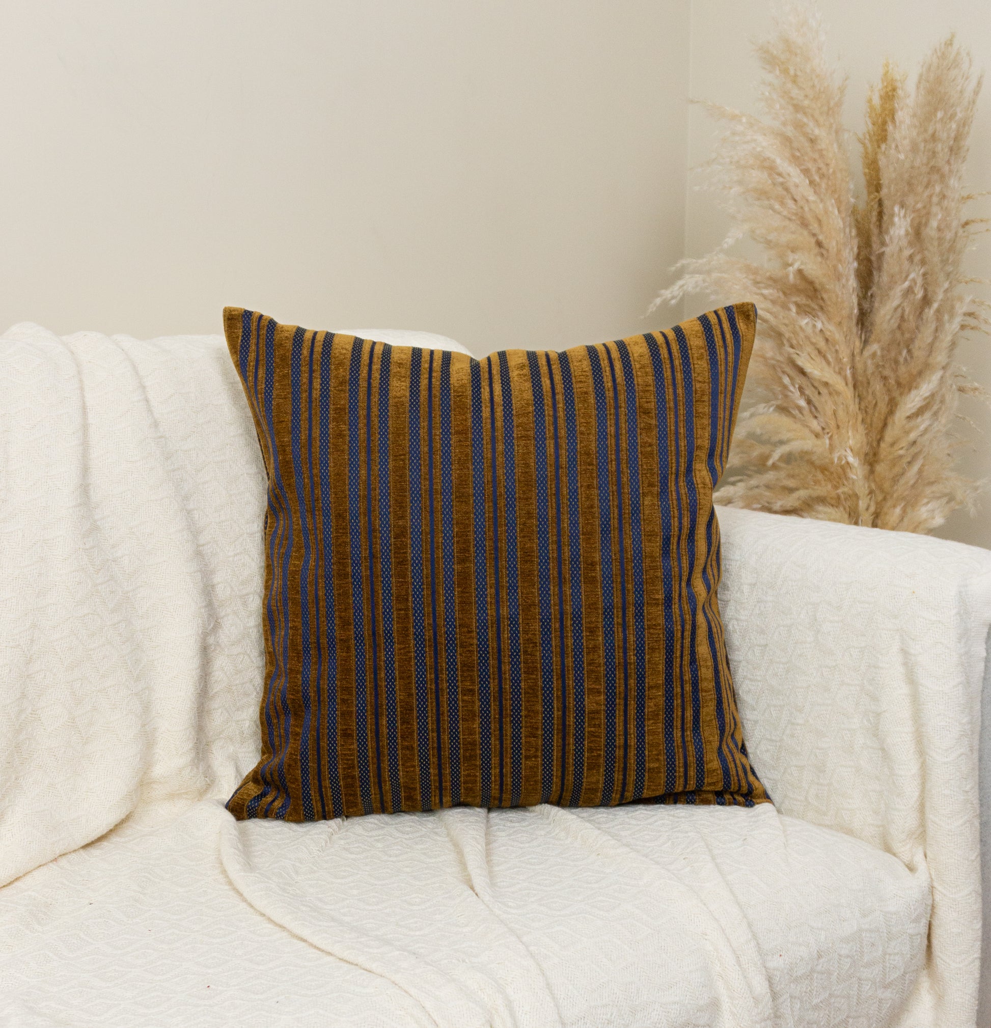 a white couch with a brown and blue striped pillow